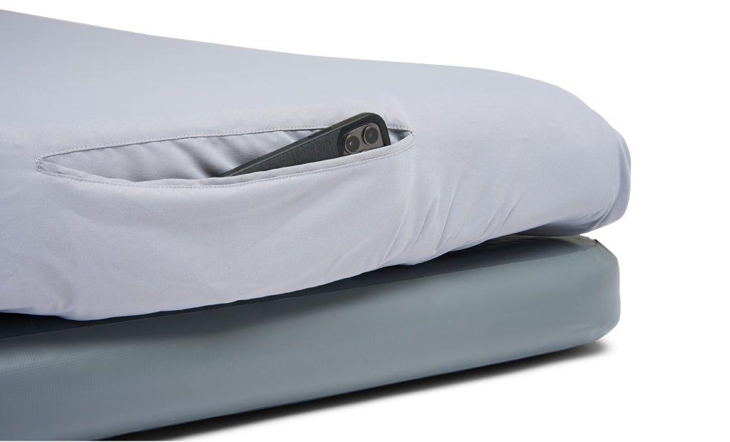 Gray mattress with a smartphone in a pocket on top, on a white background