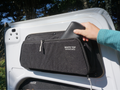 person placing item in rear van door storage pouch