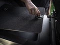 Person lifting lid to a foot storage compartment in van